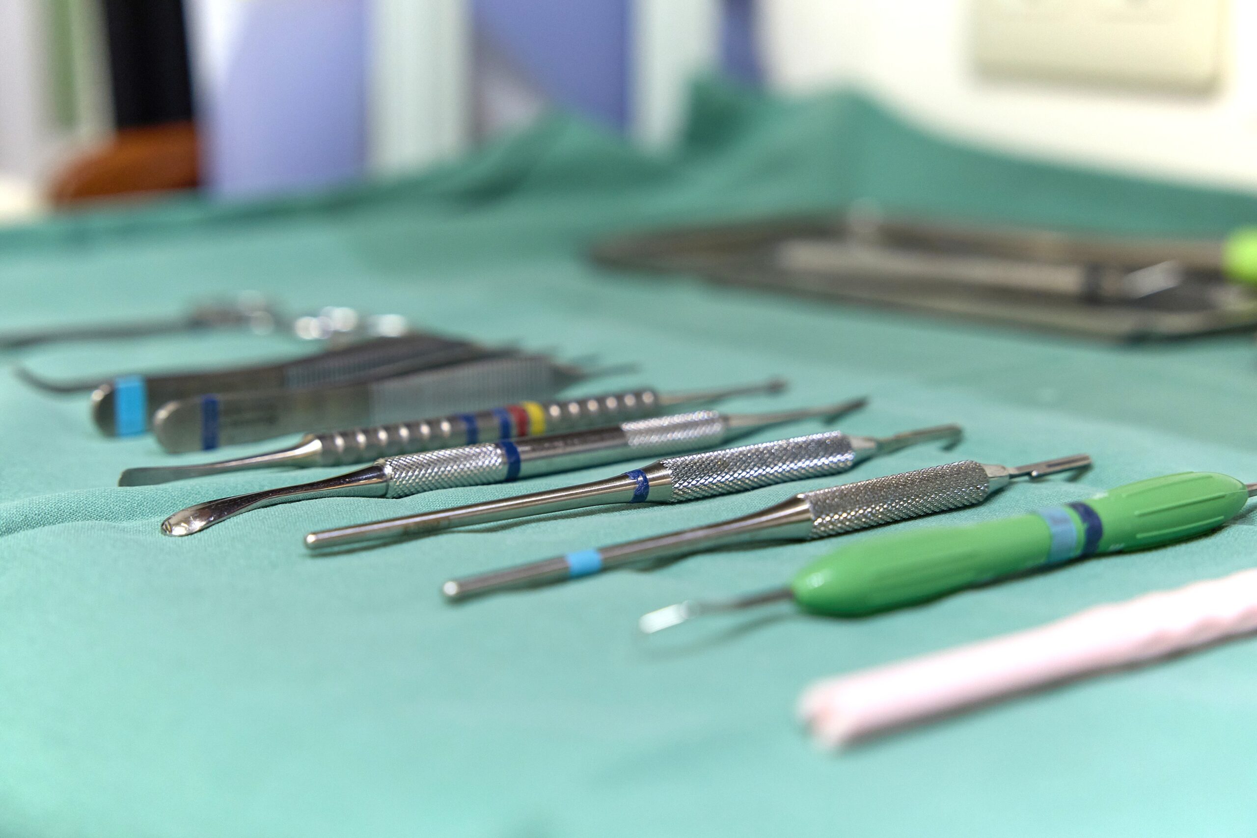 Dental instruments with textured metal heads laid out on a green surgical cloth, ready for use.